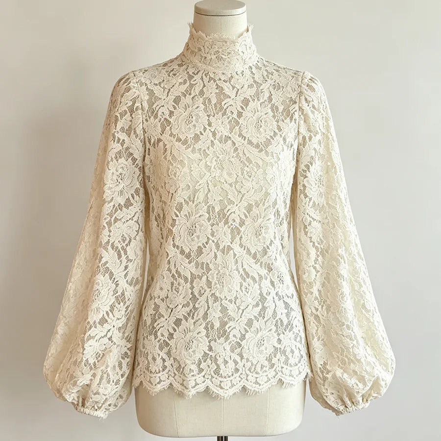 An ivory lace long-sleeve blouse with a mock neck and balloon sleeves, displayed on a cream mannequin torso against a light neutral background.